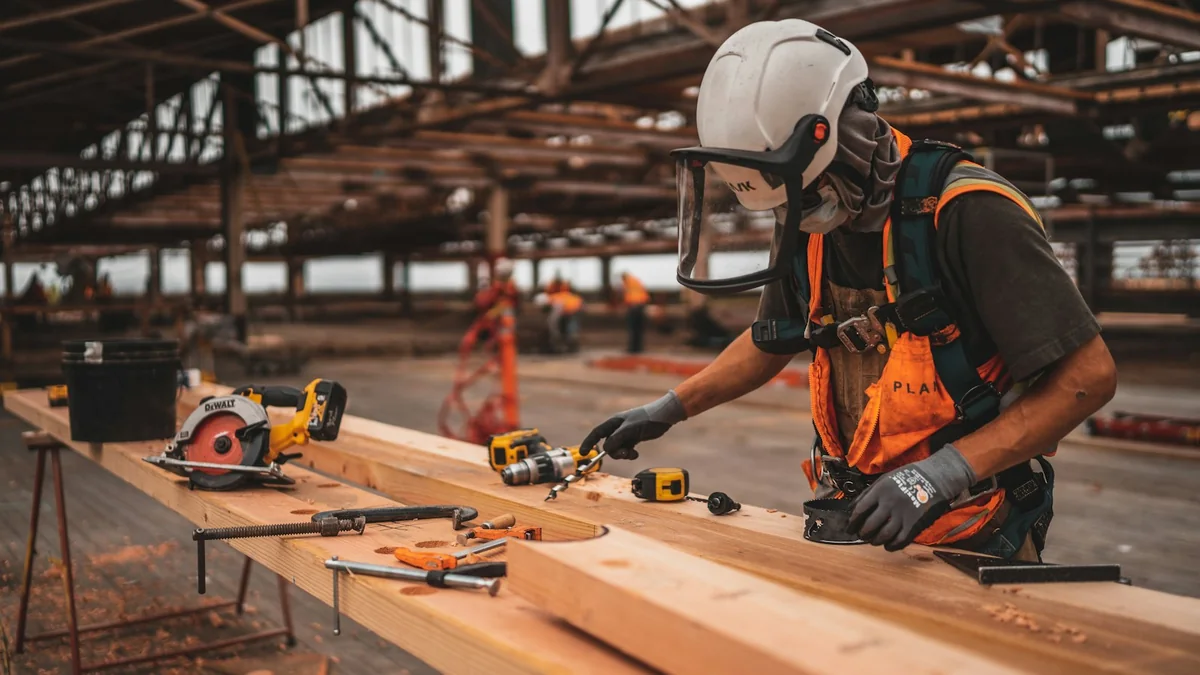 Artisan du bâtiment au travail sur un chantier, équipé de son casque et de ses outils.